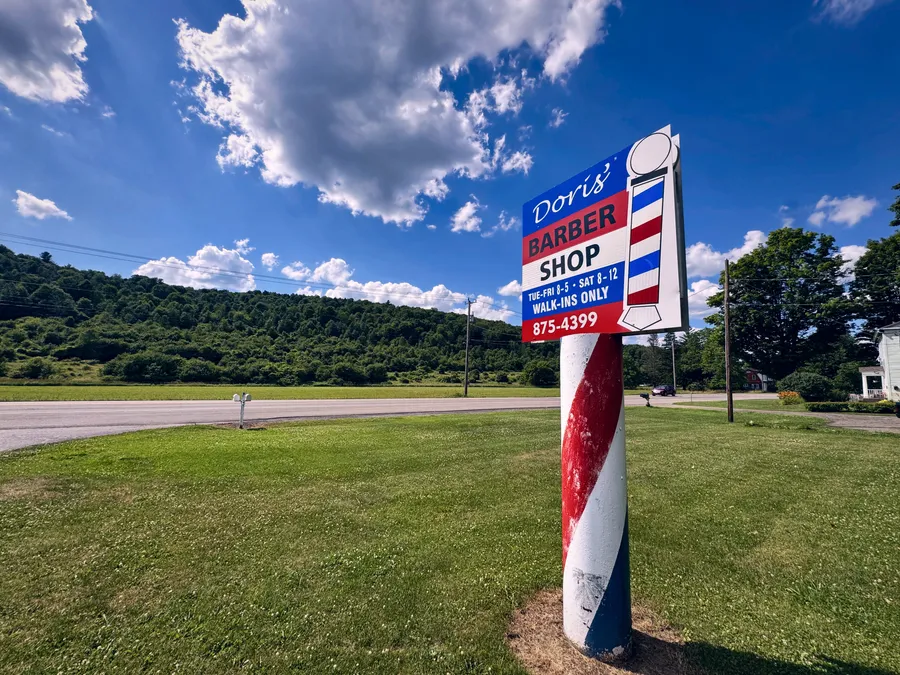 The barber-pole road sign for Doris's Barber Shop out on NY-12 in Greene.