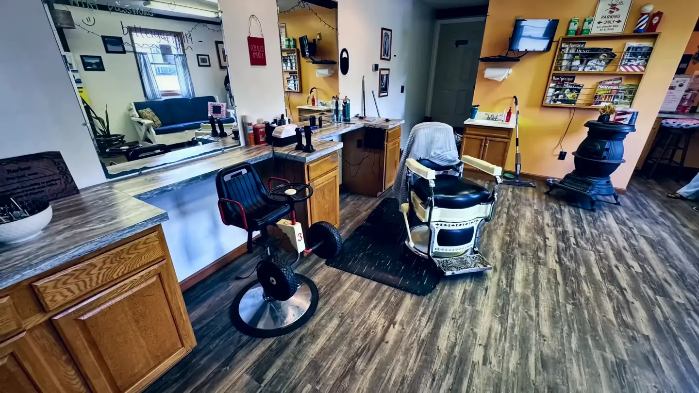 Inside Doris's Barber Shop — mirrors on the left, two barber chairs, and the TV up on the warm orange wall.
